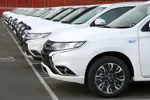 Front views of white facelifted Mitsubishi Outlander PHEVs parked in rows before heading to UK dealerships