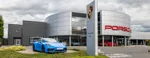 A front view of Bowker Motor Group's Porsche Centre Bolton dealership with a blue Porsche displayed