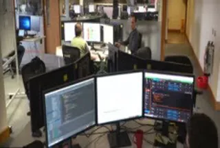 An office with people sat behind three monitors