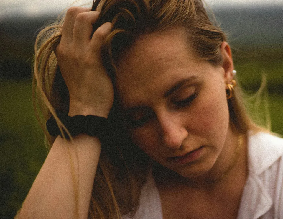 Photo of a bored woman holding her head by BĀBI on Unsplash