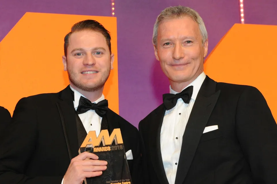 Simon Priest, centre principal,  Porsche Centre Wolverhampton, collects the award from Mark Gow, sales director, DSG Finance, right 